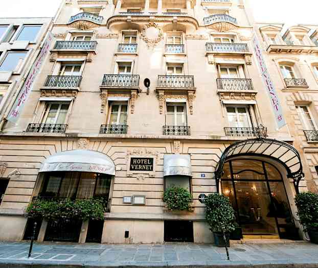 Hotell Vernet, ett klassiskt stenhus med dekorativ fasad och balkonger, huvudentré med glasdörrar och överliggande baldakin. (AI-genererad text)