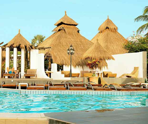 Poolområde med halmtak och solstolar. (AI-genererad text)