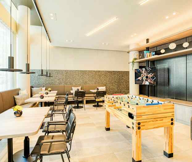 Ett modernt rum med bord, stolar och en fotbollsspelbord. (AI-genererad text)