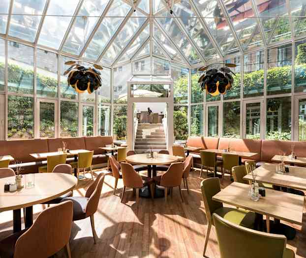 Skyddad restaurang med glasväggar, sittplatser och belysning. (AI-genererad text)