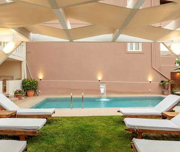 Utomhus sittområde med solstolar och en pool. (AI-genererad text)