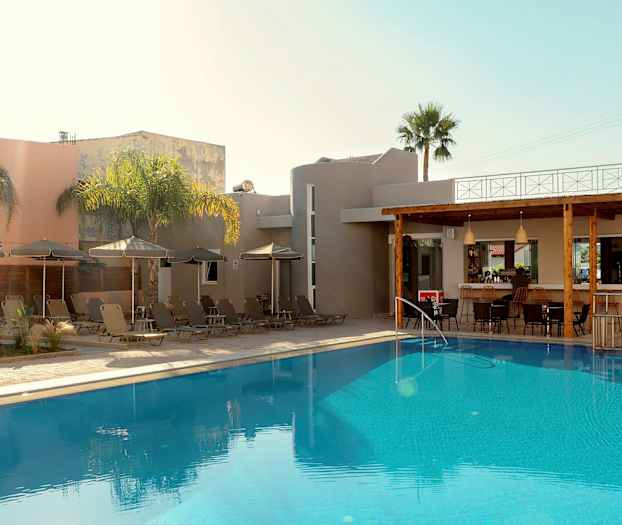 En utomhuspool vid en byggnad med solstolar och parasoller samt en bar. (AI-genererad text)