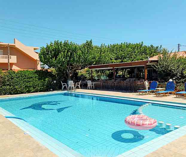 En utomhuspool omgiven av solstolar och en grönskande trädgård. (AI-genererad text)