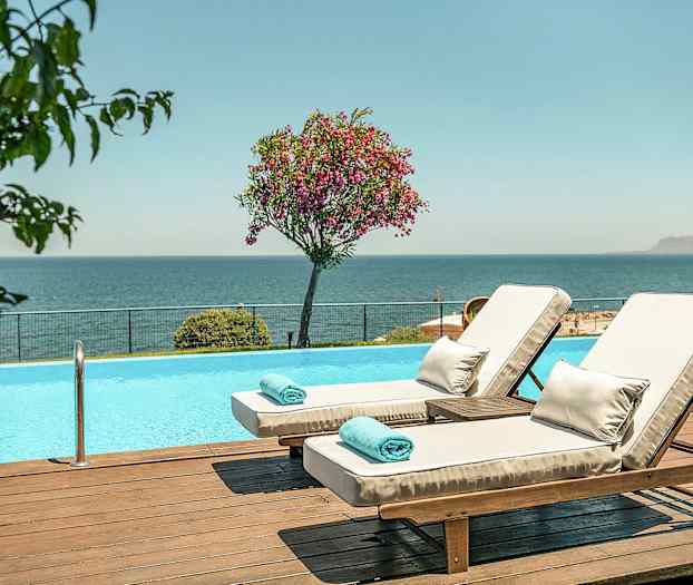 Två solstolar vid en pool med utsikt över havet. (AI-genererad text)