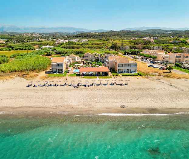 Flygfoto av strand med parasoll och semesteranläggning. (AI-genererad text)