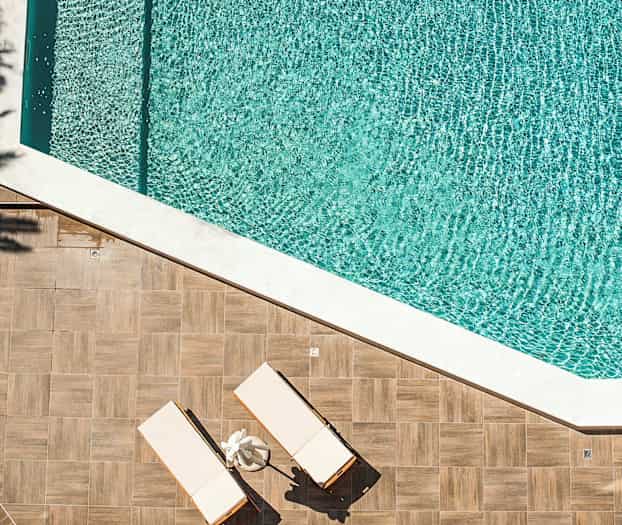 Två solstolar på en trätrall intill en swimmingpool. (AI-genererad text)