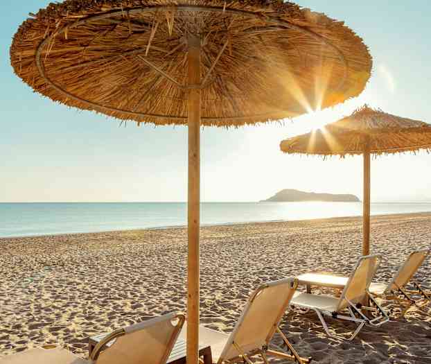 Solstolar på en sandstrand under parasoller. (AI-genererad text)