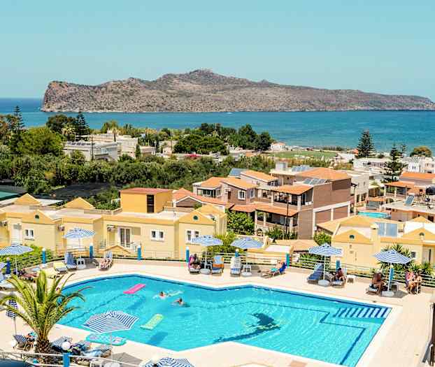 En pool med solstolar och parasoller framför en vy som inkluderar hus, grönska och hav. (AI-genererad text)