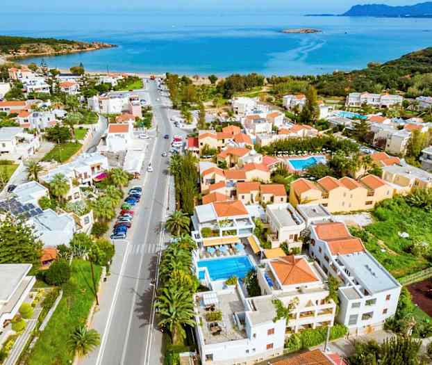 Flygbild av en kuststad med hus, pooler och hav i bakgrunden. (AI-genererad text)