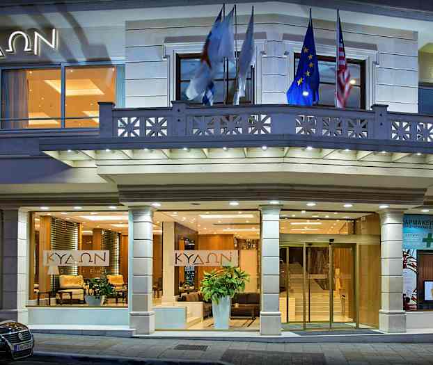 Byggnadens entré med glasdörrar, ljusa fasaddekorationer och belysning som lyser upp området. (AI-genererad text)