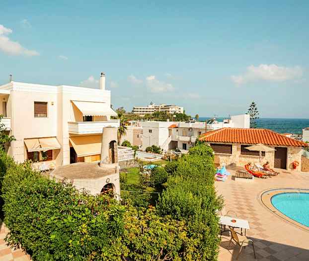 Bilden visar en utomhusmiljö med hus, gröna växter, en blå swimmingpool och solstolar vid en solig dag. (AI-genererad text)