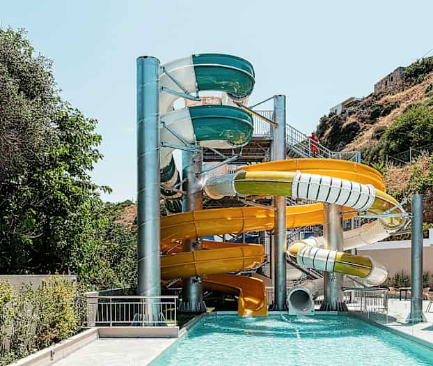 Flera färgglada vattenrutschkanor vid en utomhuspool. (AI-genererad text)