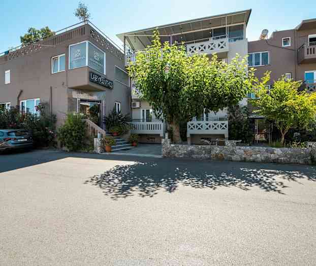 Exteriör av byggnad med inneboende och parkerade bilar framför. (AI-genererad text)