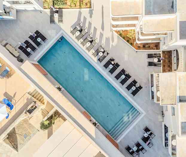 Flygfoto över en utomhuspool omgiven av solstolar och bord. (AI-genererad text)