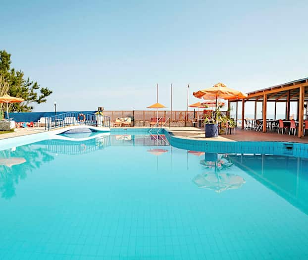 En utomhuspool med parasoll och bord bredvid. (AI-genererad text)