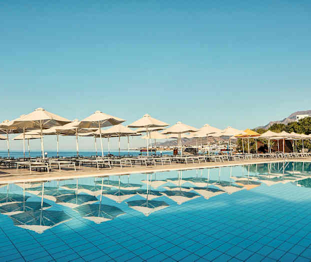 Solstolar och parasoll vid en pool med utsikt över havet. (AI-genererad text)