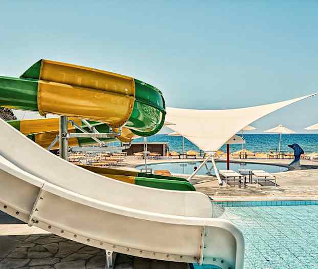 Färgglada vattenrutschbanor vid en pool nära havet. (AI-genererad text)