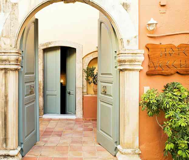 Bilden visar en ingång med en båge, öppna dubbeldörrar, en skylt som lyder 'Hotel Vecchio' och växtlighet runt omkring. (AI-genererad text)