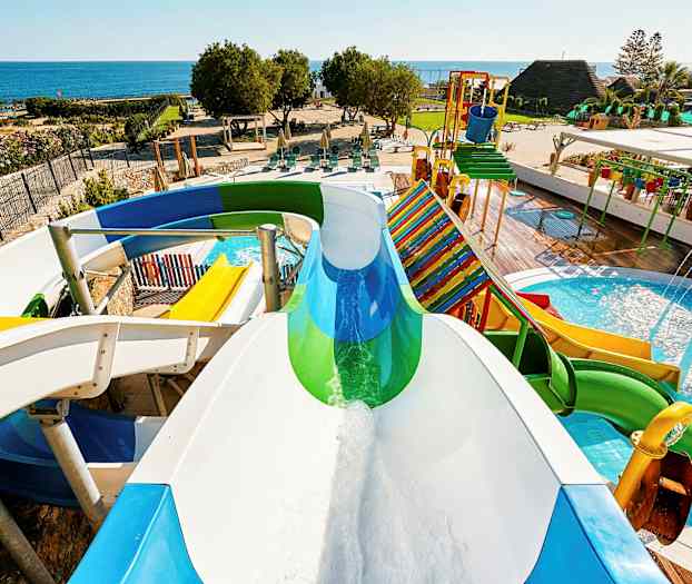 Vattenrutschbanor och poolområde med havet i bakgrunden. (AI-genererad text)