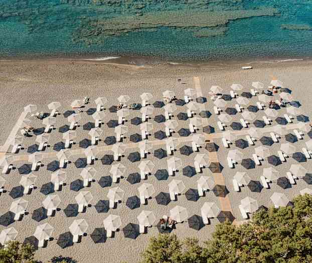 Strand med parasoller och solstolar i rader vid havet. (AI-genererad text)