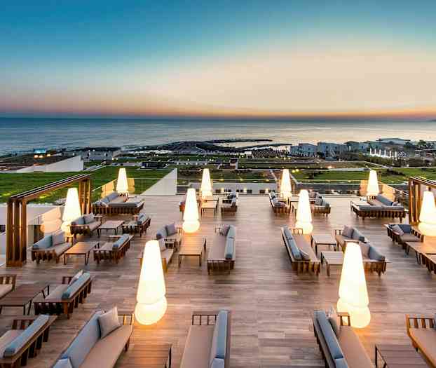 Moderna utomhusmöbler med upplysta lampor på en stor terrass med havsutsikt. (AI-genererad text)