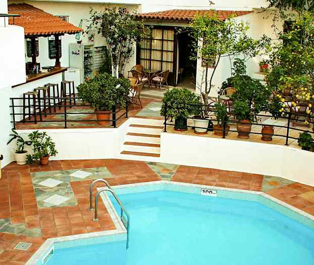 En utomhuspool med närliggande matplats och bar, omgiven av grönska. (AI-genererad text)