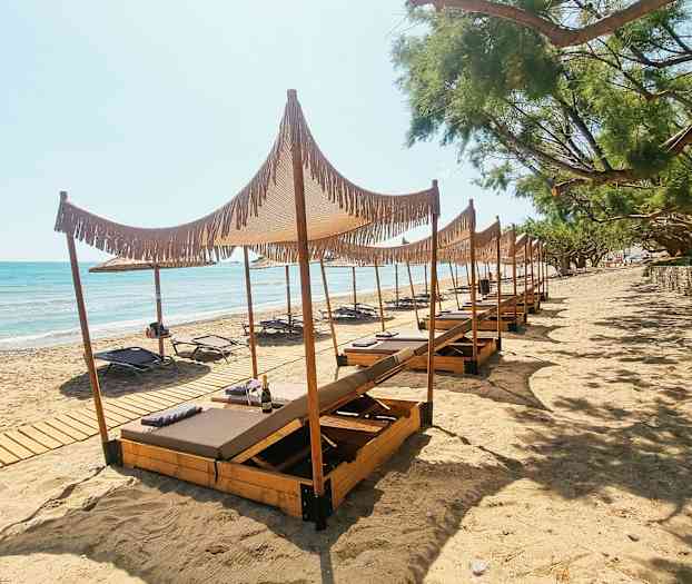 Bild av en sandstrand med solstolar och träparasoller. (AI-genererad text)