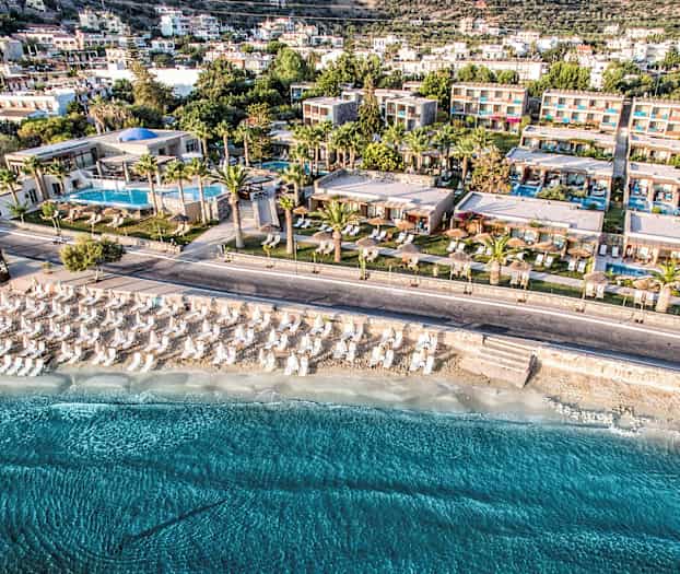 Luftbild av en semesteranläggning vid stranden med parasoller och solstolar. (AI-genererad text)