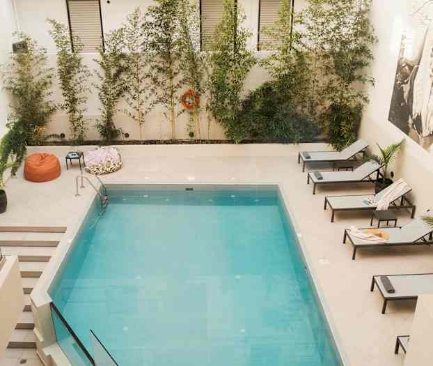 En swimmingpool med solstolar och grönska runtom. (AI-genererad text)