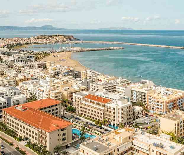 Flygfoto av en stad vid kusten med sandstrand och båthamnar. (AI-genererad text)