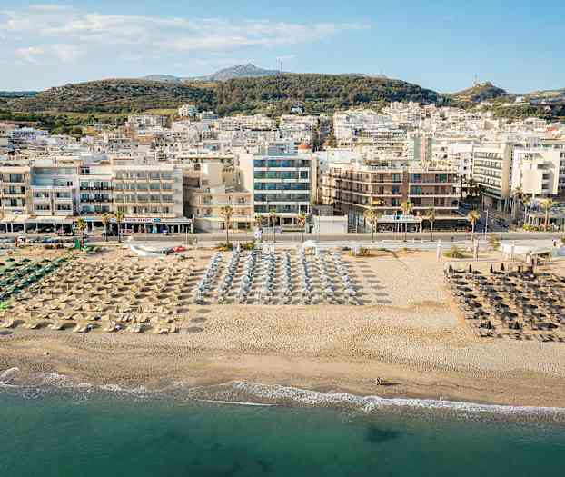En vy över en strand med parasoller och solstolar, och en stad i bakgrunden. (AI-genererad text)