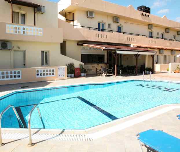 En utomhuspool vid ett hotell med solstolar och byggnaden i bakgrunden. (AI-genererad text)