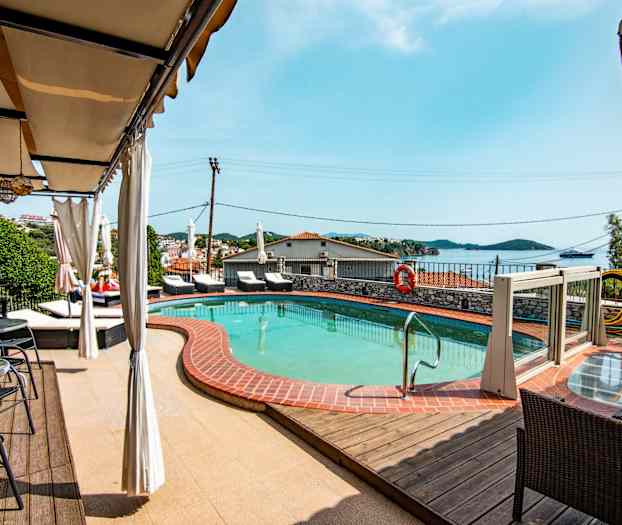 En pool med omgivande solstolar och en utsikt över havet. (AI-genererad text)