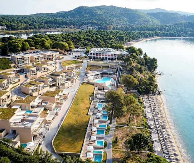 Flygfoto av ett strandnära hotell med pooler och solbäddar. (AI-genererad text)