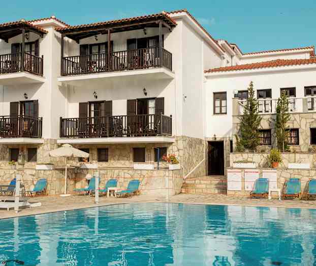 Vit byggnad med balkonger och en pool framför. (AI-genererad text)