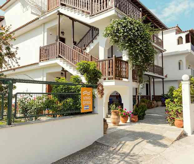 Vit byggnad med trappor och blomsterdekorationer utomhus. (AI-genererad text)