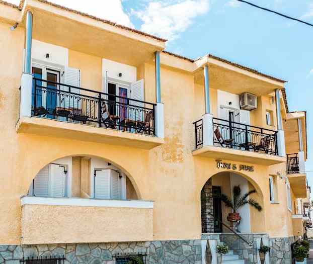 Exteriör av en gul byggnad med balkonger och en entré. (AI-genererad text)