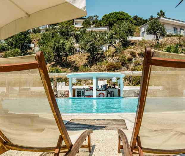 Två solstolar vid kanten av en pool med en bar i bakgrunden. (AI-genererad text)