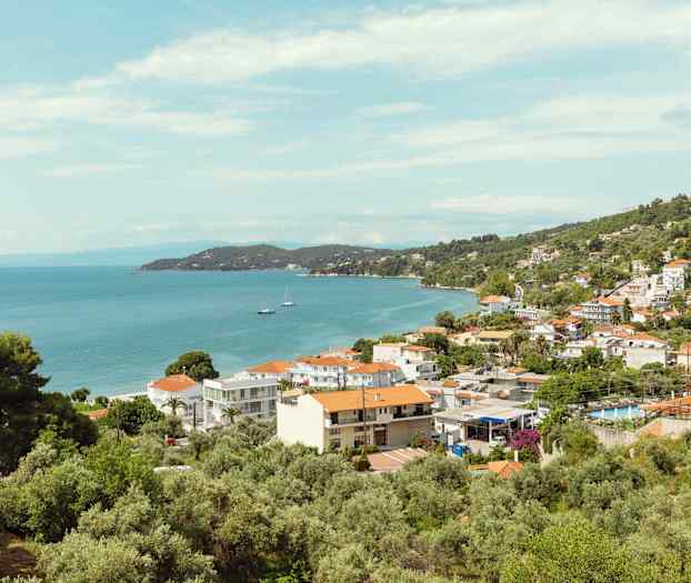 Vy över en kuststad med hus, träd och hav. (AI-genererad text)