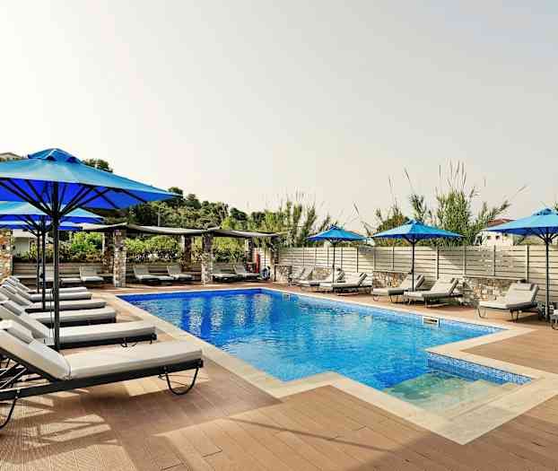 En utomhuspool omgiven av solstolar och parasoller. (AI-genererad text)