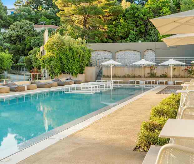 En utomhuspool med solstolar och parasoller samt omgivande grönska. (AI-genererad text)