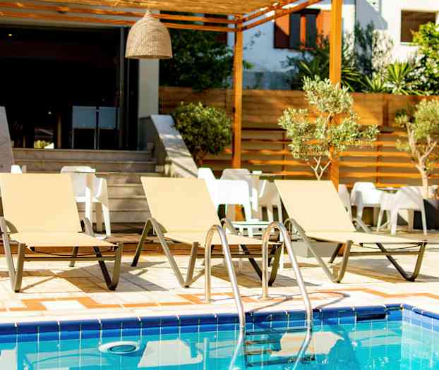 Tre solstolar vid en pool med bord och stolar i bakgrunden. (AI-genererad text)