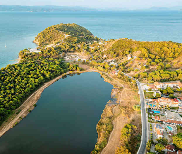 Luftbild av en kust med skog, en stor insjö och byggnader. (AI-genererad text)
