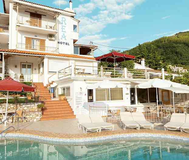 En hotellbyggnad med flera nivåer och en pool i förgrunden. (AI-genererad text)