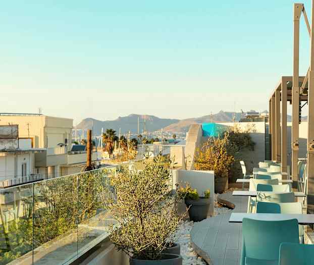 Bild av en takterrass med sittplatser och planteringar, med utsikt över staden och berg i bakgrunden. (AI-genererad text)