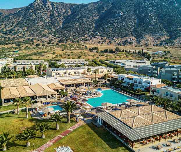 Bild av ett semesterhotell med pool och omgivande byggnader, beläget nära en bergig landskap. (AI-genererad text)