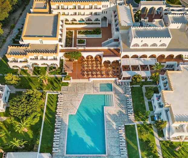 Flygfoto av ett semesterhotell med poolområde och omgivande byggnader. (AI-genererad text)