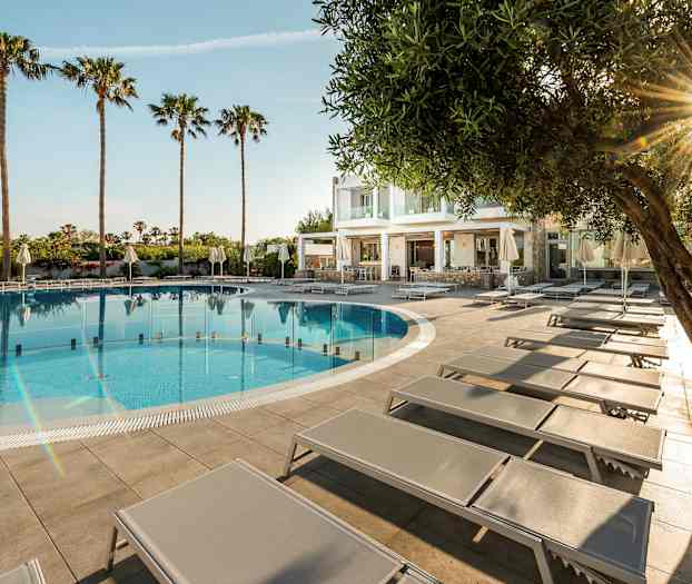 Utomhuspool med solstolar och palmer i bakgrunden. (AI-genererad text)