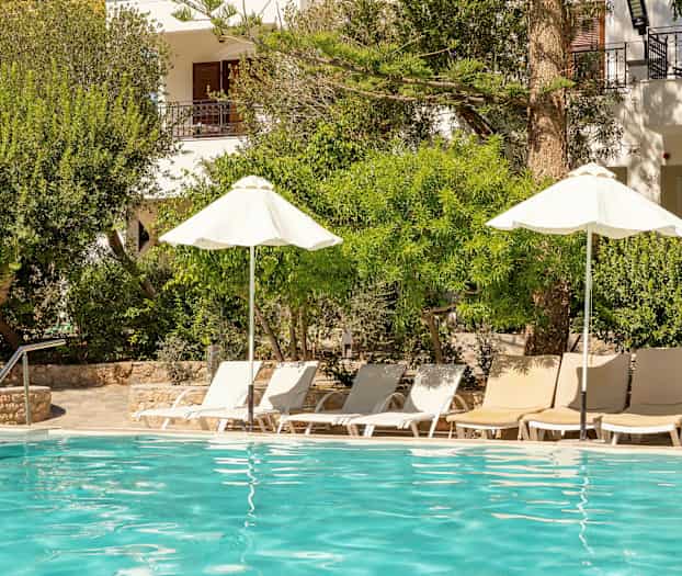 En utomhuspool med solstolar och parasoller omgiven av grönska. (AI-genererad text)