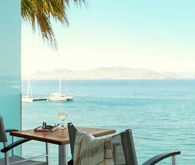 Utsikt över havet från en altan med bord och stolar. (AI-genererad text)